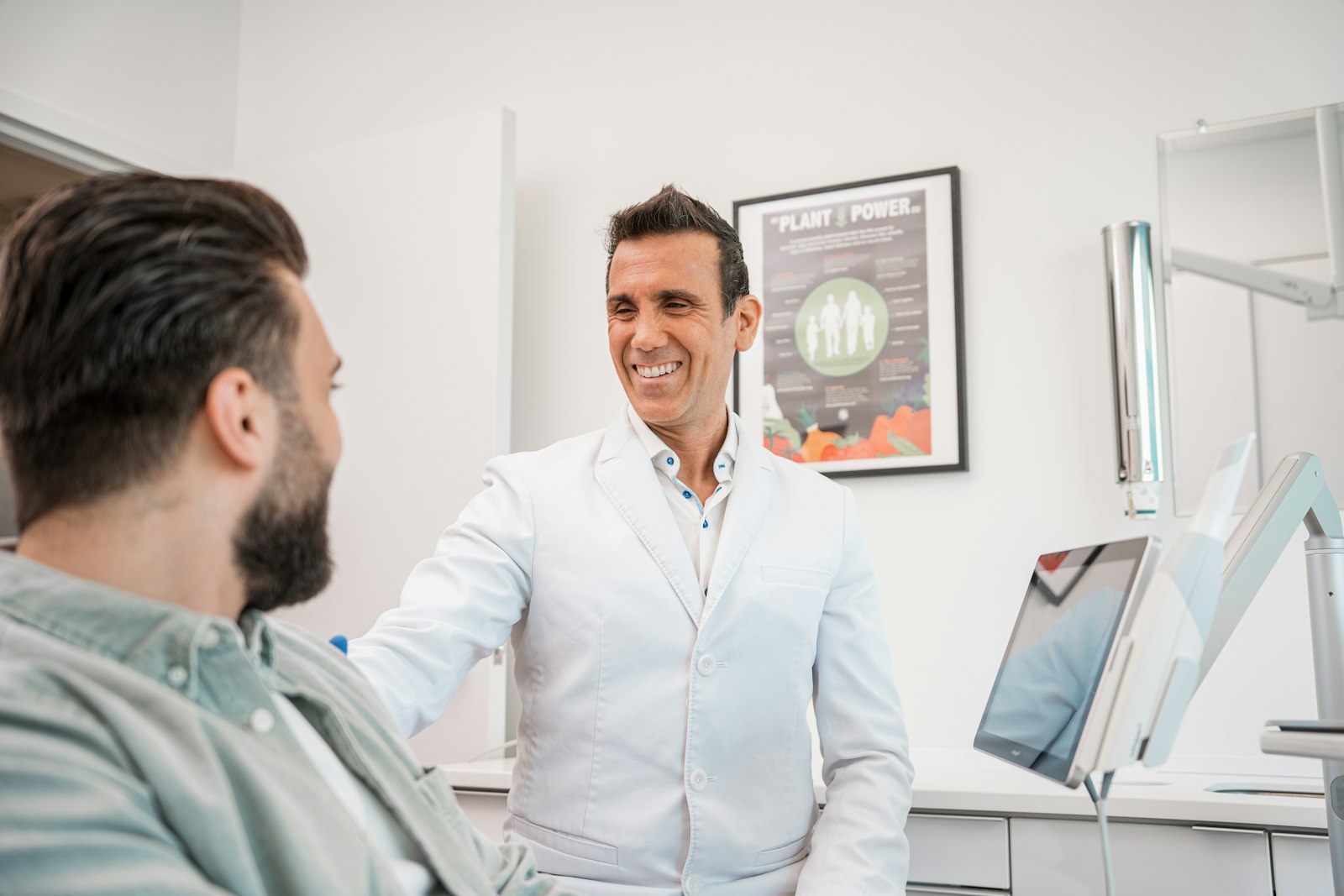 A dentist talking with a smiling patient in a bright consultation room